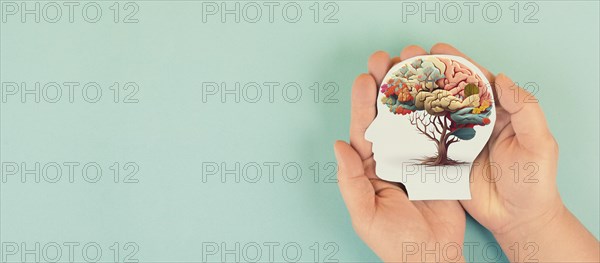 Hands holding paper head, human brain with flowers, self care and mental health concept, positive
