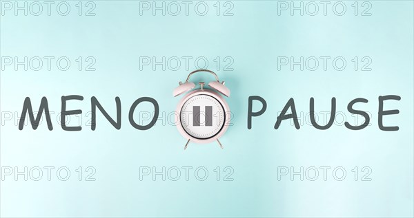 Alarm clock with pause sign and the word menopause, hormone replacement therapy