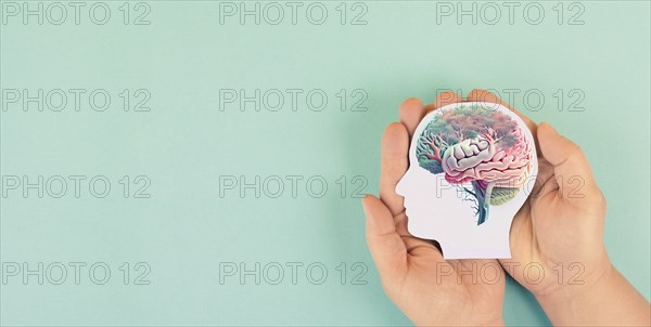 Hands holding paper head, human brain with flowers, self care and mental health concept, positive