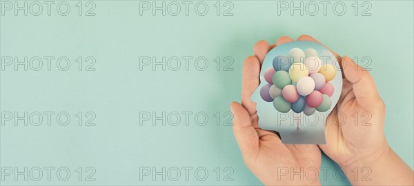 Hands holding head, brain with colorful ballons, self care, freedom and mental health concept,