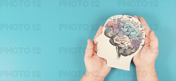 Hands holding paper head, human brain with flowers, self care and mental health concept, positive