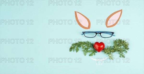 Easter rabbit face with a heart shaped nose, whiskers from carrot leaves and eyeglasse, holiday