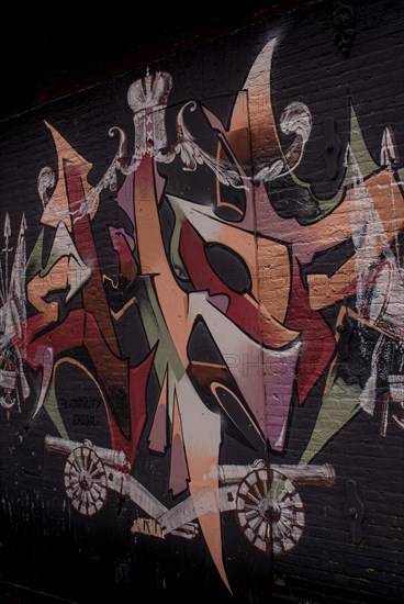 A colourful graffiti on a black brick wall with abstract shapes and a crown, Amsterdam, Netherlands