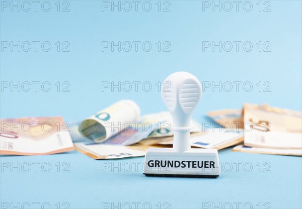 Euro banknotes and a stamp with the german word forr property tax, new law in Germany on houses