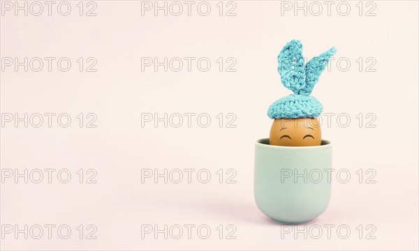 Cute easter bunny or rabbit with a smiling egg face in a cup, spring holiday, greeting card