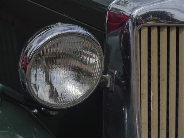 Close-up of a headlight of a green vintage car with chrome accents, winterswijk, gelderland, the