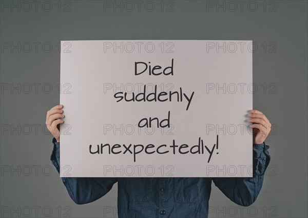 Died suddenly and unexpectedly, young man holds sign, clarification of the increase of mortality,