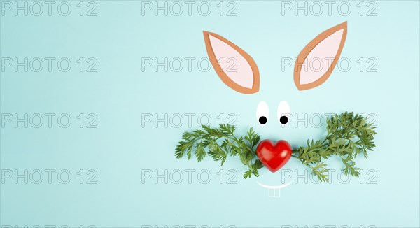 Easter bunny face with a heart shaped nose and whiskers from carrot leaves, holiday greeting card,