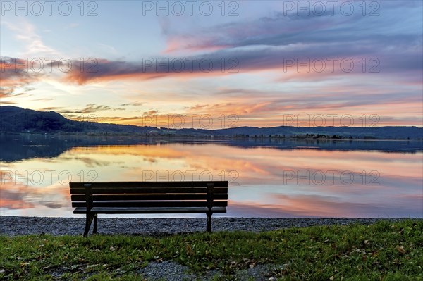 Bench at Lake Kochel, reflection of sun and clouds at sunset, calm water, Kochel am See, Bavarian