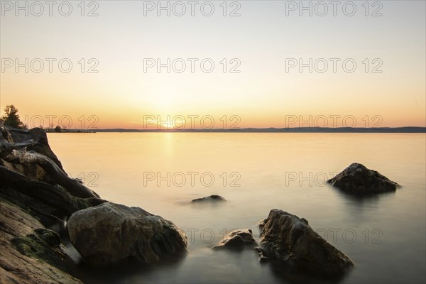 Sunset on the shore of a lake in summer. Colourful sky with a wide view of the horizon. Natural