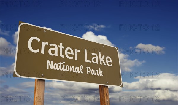 Crater lake national park (oregon) road sign against blue sky and clouds