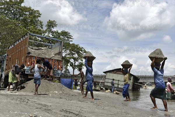 Labourer carries extracted sand from Beki River, in Barpeta district in Assam, India on Sunday