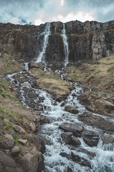 Idyllic waterfall Budareyrarfoss with river at Seydisfjordur, Iceland, vertical shot, Europe
