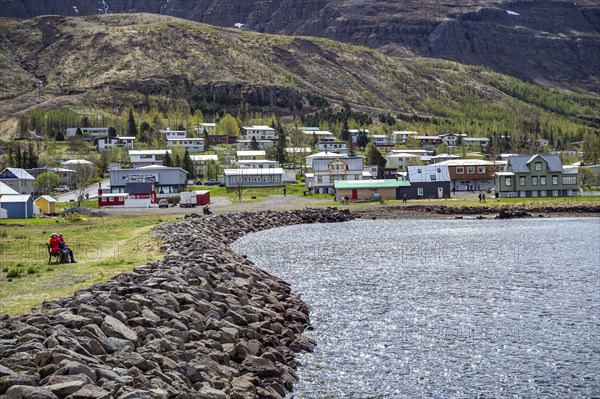 Residential area with residential buildings and houses behind a lake in front of a mountain in