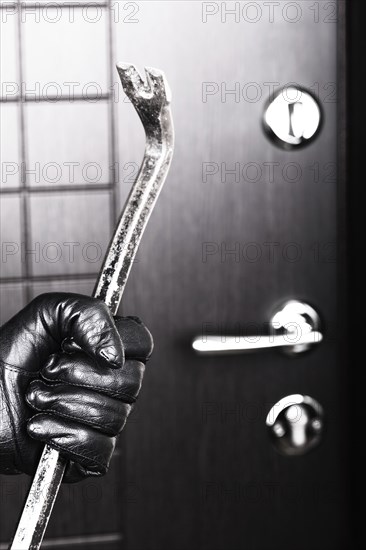 Crime scene, criminal thief or burglar hand in gloves holding metal crowbar break opening home door
