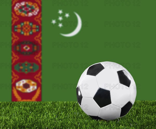 The Turkmen flag and soccer ball on the green grass