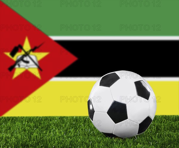 The Mozambique flag and soccer ball on the green grass