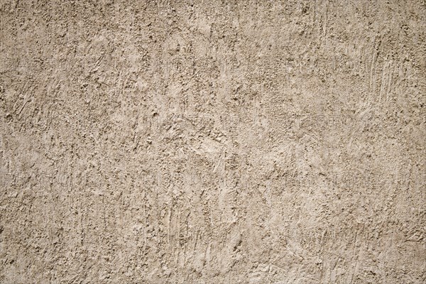 A close-up of a beige stucco wall with a rough textured surface
