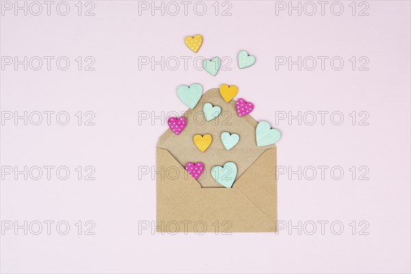 Valentine day greeting card, envelope with hearts on pastel background, love symbol, flat lay
