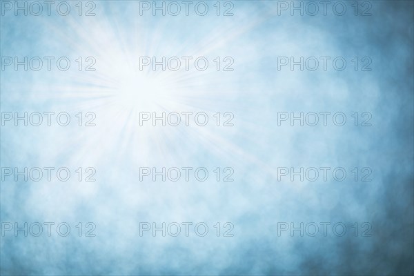 Blue bokeh background with defocused round lights and sunbeams, flare overlay