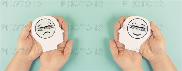 Holding a head with a sad and a happy face in the hands, mental health concept, positive and