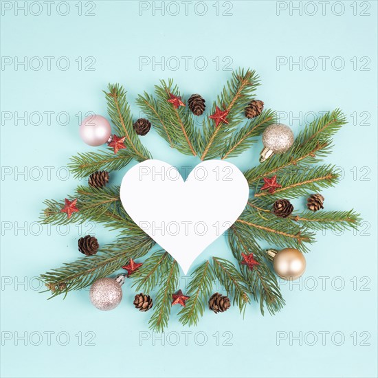 Christmas holiday background in heart shape, frame with fir branches, baubles and pine cones,