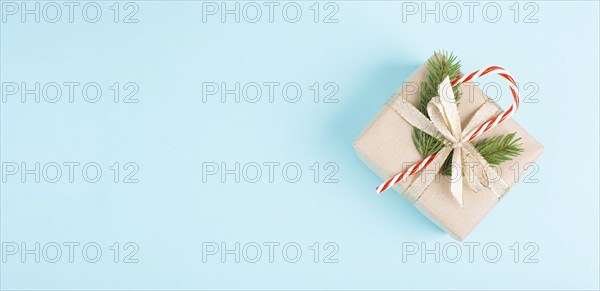 Christmas holiday greeting card with little gift box, candy cane, ribbon and fir branches, blue