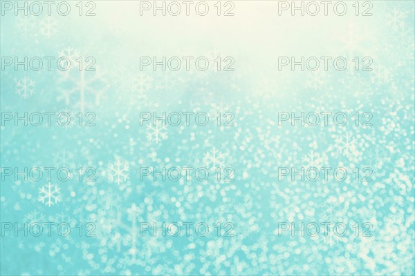 Blue bokeh background with snowflakes for christmas, defocused round lights and sunbeams, flare
