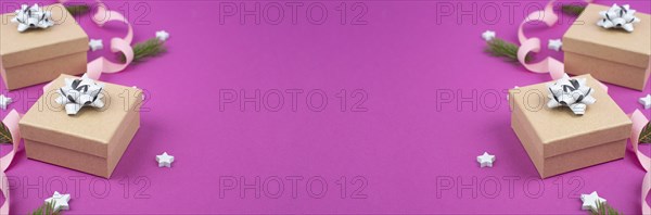 Christmas holiday background with little gift boxes, stars and fir branches, pink trendy background