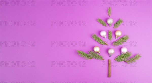 Christmas tree made from fir branches, pink baubles and a cinnamon stick as the trunk, greeting