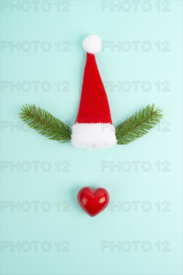 Face of a reindeer with a red heart nose, fir antlers and a santa claus hat, merry christmas