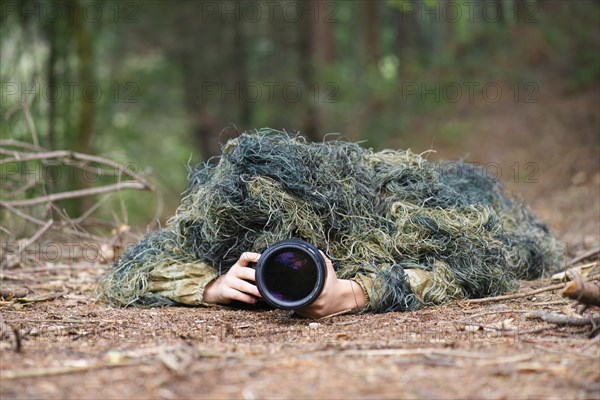 Photographer wearing camouflage clothing in the forest, wildlife animal photography with a camera