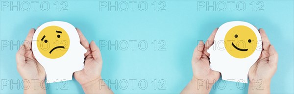 Holding a head with a sad and a happy face in the hands, mental health concept, positive and
