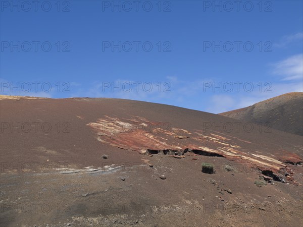 Red rocky landscape with barren ground and blue sky, arrecife, Lanzarote, Canary Islands, Spain,