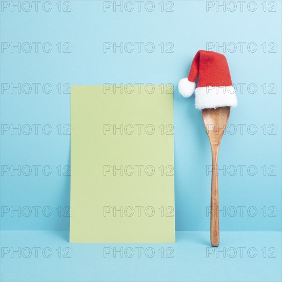 Blank paper with a wooden spoon and a red Santa Claus hat, christmas greeting card, copy space for