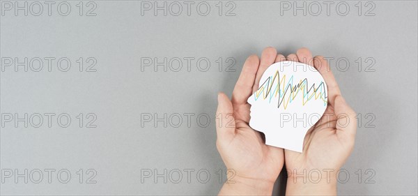 Holding a head in the hands, epilepsy disorder awareness, brain waves, mental health care, paper