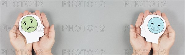 Holding a head with a sad and a happy face in the hands, mental health concept, positive and