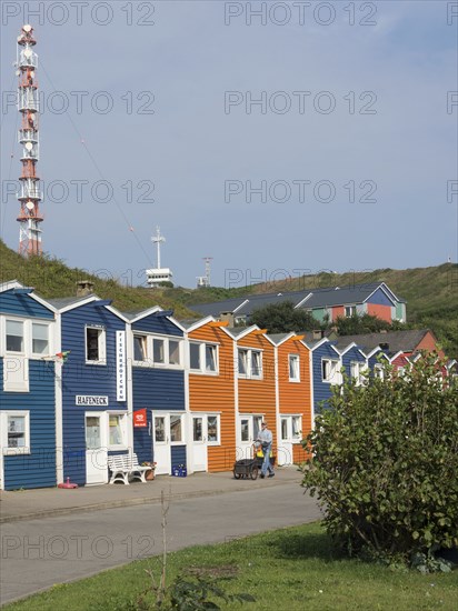 Colourful houses next to a large lighthouse on a quiet street, Heligoland, North Sea, Germany,