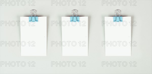 Blank white papers with a paperclip on a gray colored background, copy space for text, reminder or