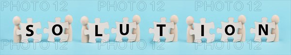 The word solution is standing on puzzle pieces, working as a team together to reach a goal,