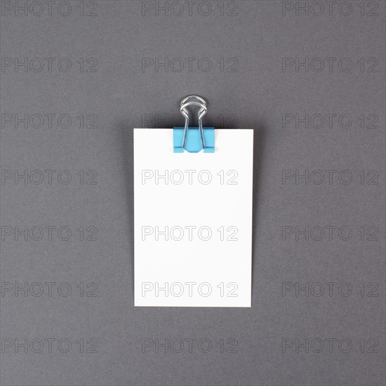 Blank white paper with a paperclip on a gray colored background, copy space for text, reminder or