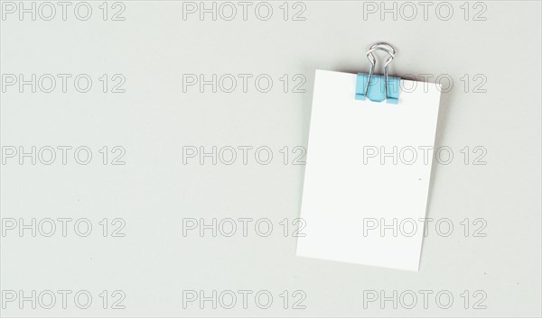 Blank white papers with a paperclip on a gray colored background, copy space for text, reminder or