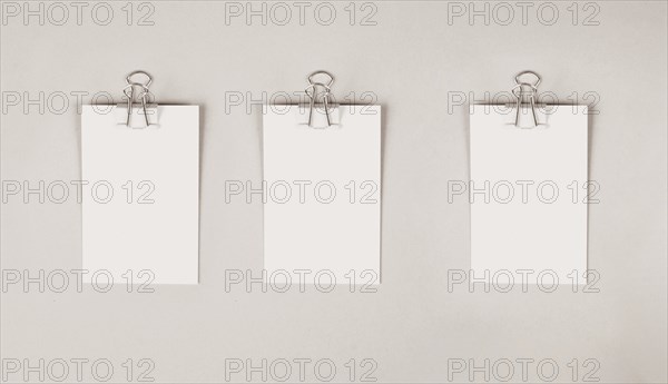 Blank white papers with a paperclip on a gray colored background, copy space for text, reminder or