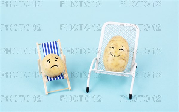 Potatoes with funny faces sitting in lounge chairs and having a conversation, the small one is sad,