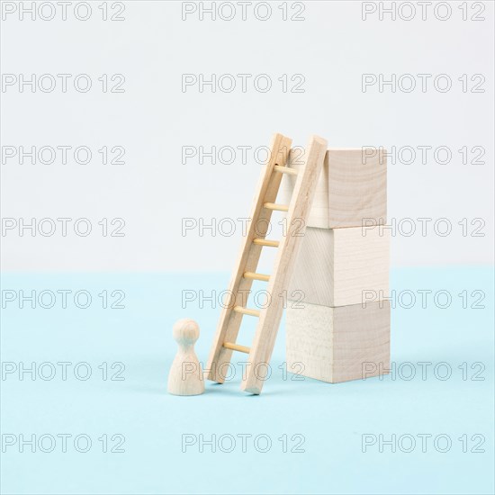 Man is standing next to a ladder, climbing up in career, having a goal, brainstorming for ideas,