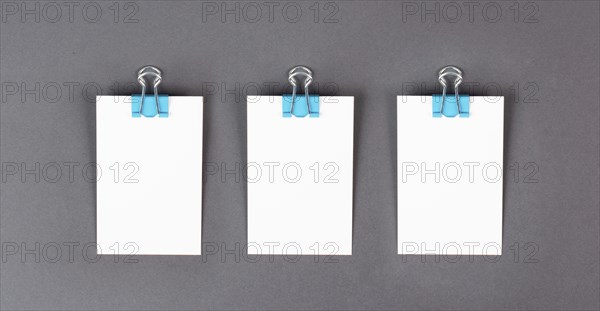 Blank white papers with a paperclip on a gray colored background, copy space for text, reminder or