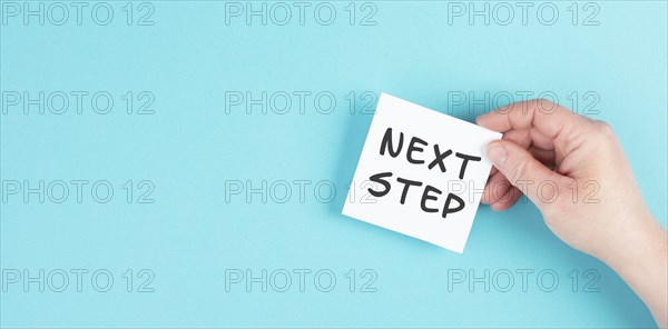 The phrase next step is standing on a paper, having new goals and strategies, making plans for