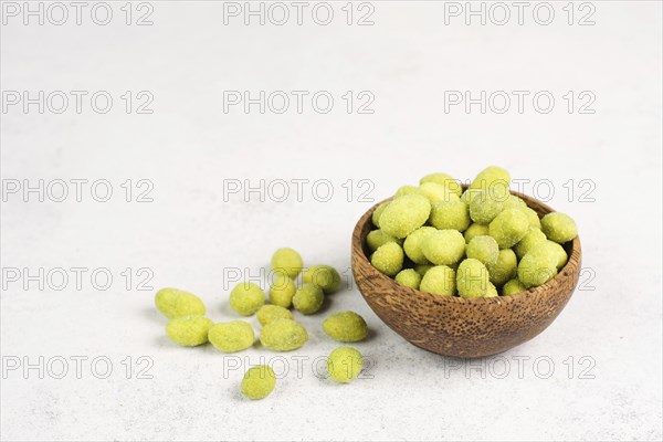 Pile of green wasabi coated peanuts in a bowl, spicy snack, oriental food