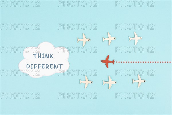 Group of airplanes flying, red plane thinks different and takes the opposite direction, against the