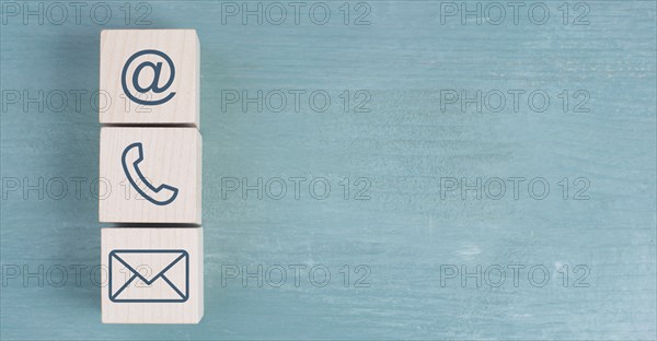 Signs for e-mail, phone and newsletter on wooden blocks, blue background, copy space for text,